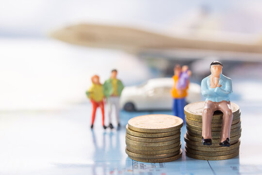  Businessman figures sitting on the coin with blurred car and airplane background.