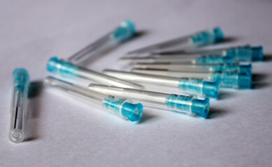 Many blue medical needles on a white background.