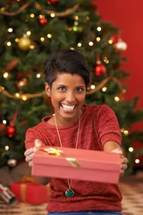 Foto op Canvas Christmas, portrait and woman with gift giving for celebration offer and kindness on festive holiday. Smile. person and face with happiness for present, share and special event in living room © peopleimages.com