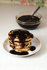 Stack of american pancakes or fritters with jam in plate on white table, delicious dessert for...