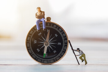 Miniature people- Figures businessman, is sitting on a compass area