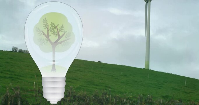 Animation of tree in light bulb over wind turbine in green landscape