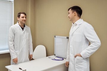Two male doctors discussing patient treatment in hospital