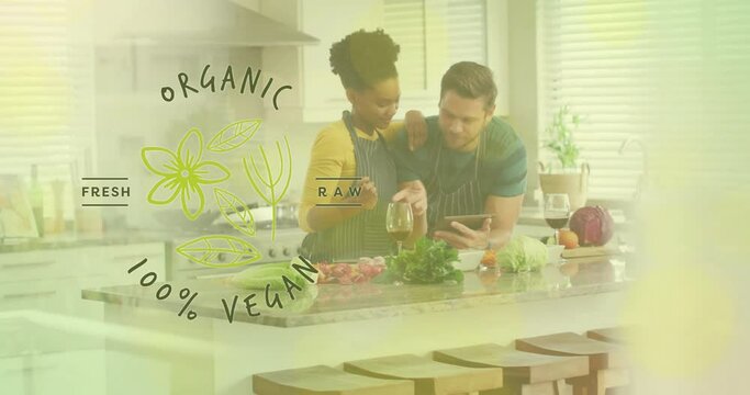 Animation of organic vegan text over diverse couple preparing healthy meal in kitchen
