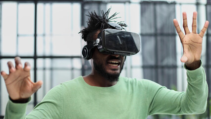 Cool handsome african american man put on virtual reality goggles for the first time in the office.