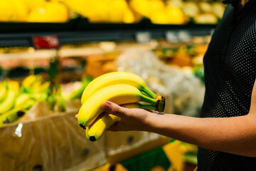 Boy holding a bunch of bananas in the supermarket