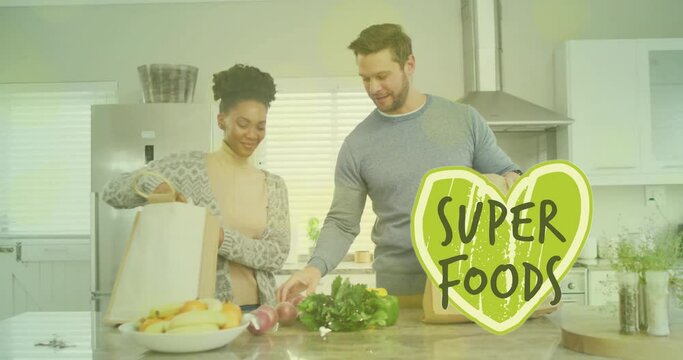 Animation of super foods text over diverse couple preparing healthy meal in kitchen