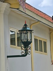 Classic green lamps adorned with red and cream accents, set against a white wall. Behind them, a...