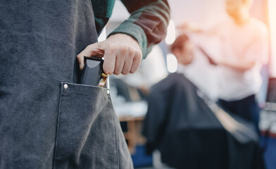 Barber shop banner. Closeup hairdresser holds hair clipper on barbershop background, with sunlight