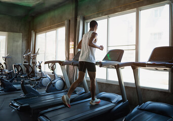 Back side of asian sportman runner running on treadmill in fitness club. Cardio workout. Healthy lifestyle, guy training in gym. Sport running concept. - obrazy, fototapety, plakaty