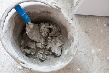 Mortar is placed in a bucket with a trowel ready for use.