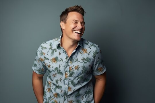 Portrait of a laughing young man in a blue shirt on a gray background