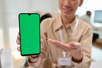 Smartphone with green screen in hands of smiling bank manager
