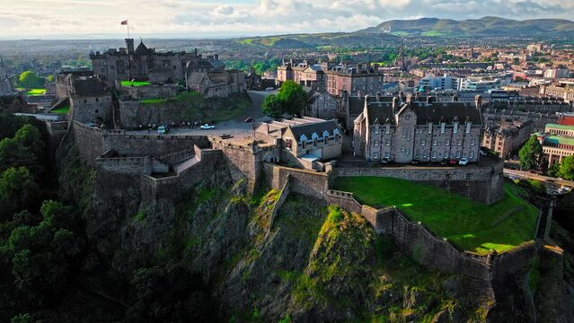 Aerial view of Edinburgh Castle with green gardens in Scotland. Historic castle and barracks housing the Crown Jewels and National War Museum of Scotland stands on Castle Rock.
