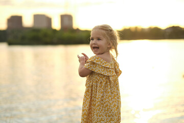 small girl faces an expansive lake at dusk, clutching a bundle of daisies. The moment epitomizes the serenity and mental clarity found in simple, natural settings