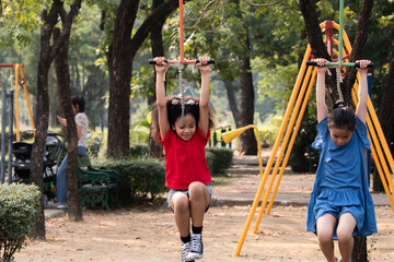 Diversity children playing in playground hanging from a yellow bar, Joyous healthy kids competing with monkey bar enjoying in park, carefree childhood outdoors activities, moments of fun and strength - Powered by Adobe