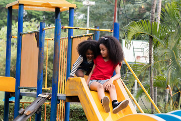 Diversity children adopted playing in playground, Joyous kids appear from playground tunnel,...