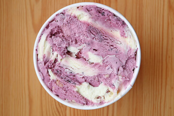 Top view of blueberry yogurt ice cream in a big cup on wooden table