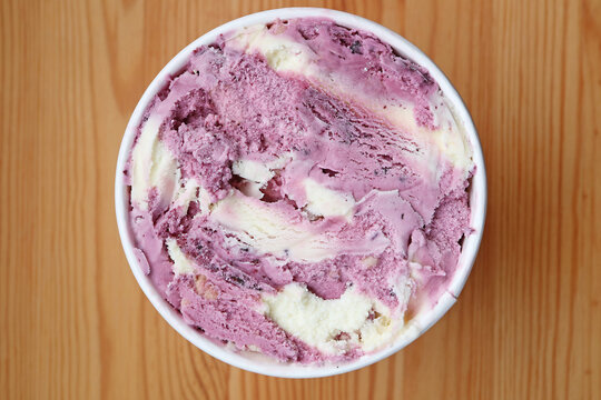 Top view of blueberry yogurt ice cream in a big cup on wooden table