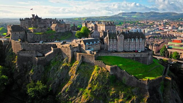 Aerial view of Edinburgh Castle with green gardens in Scotland. Historic castle and barracks housing the Crown Jewels and National War Museum of Scotland stands on Castle Rock.
