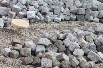 Heap of cobblestones prepared for a paving project lies beside a path