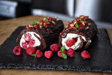 Sweet chocolate roll with whipped cream and raspberries