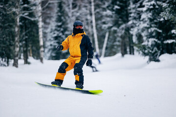 Fototapeta na wymiar Freeride snowboarding in Sheregesh Ski Resort on background snowy forest. Man snowboarder rides through snow, explosion
