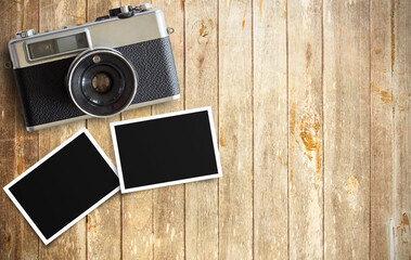 Vintage film camera and two blank photo frames on wooden table
