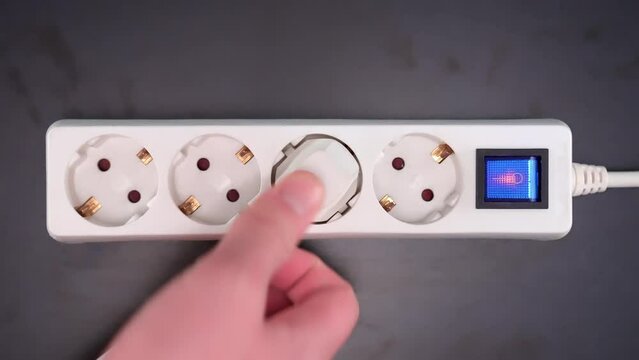Electrical extension cord with electrical plug. Extension cord on a gray background. The black and white plug are plugged into the socket in the extension cord.