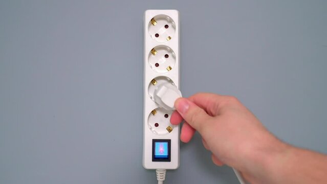 Electrical extension cord with electrical plug. Extension cord on a gray background. The black and white plug are plugged into the socket in the extension cord.