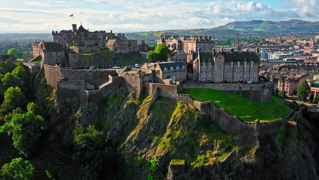 Aerial view of Edinburgh Castle with green gardens in Scotland. Historic castle and barracks housing the Crown Jewels and National War Museum of Scotland stands on Castle Rock.

