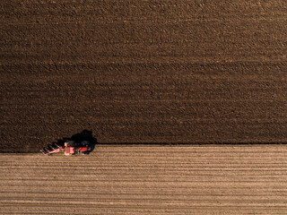 Top-down shot capturing a tractor plowing the land, creating patterns in the soil