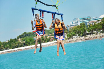 Mother and son parasailing over the Mediterranean Sea, Türkiye in mid-summer. Family and summer...