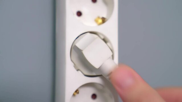 Electrical extension cord with electrical plug. Extension cord on a gray background. The black and white plug are plugged into the socket in the extension cord.