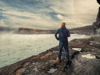 Man looking at stunning landscape with ocean and cliff and low cloudy sky. Aran island, county...