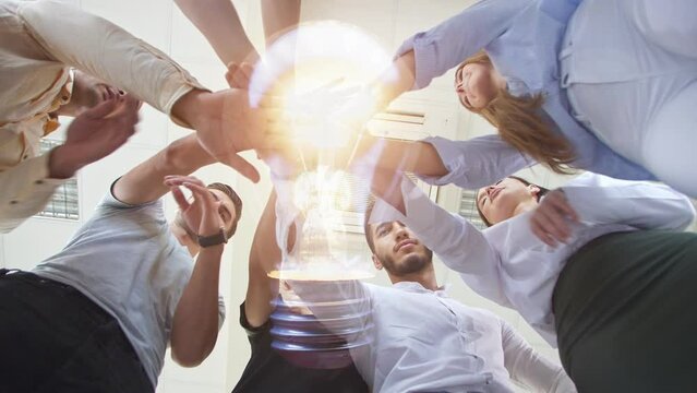 A group of young people standing in a circle extend their hands to the center where an electric lamp is flashing. The concept of friendship and spending time together. Startup idea. CG