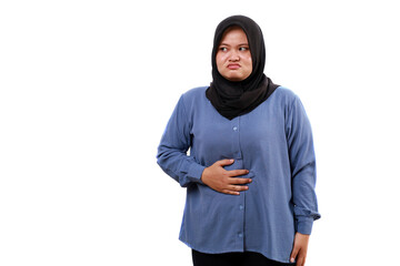 Unhappy asian muslim woman feels hungry, hand holding stomach while looking sideways
