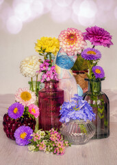 Colorful flowers in various colorful bottles and vases