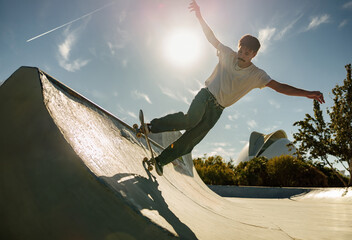 A young man doing tricks on his skateboard at the skate park. Active sport concept