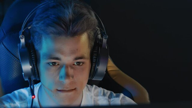 Focused serious teen gamer in headset playing PC video game at computer club. E-sport championship tournament, cyber sport team. Multiplayer online competition real-time strategy tactical shooter