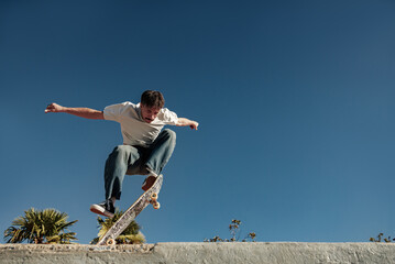 A young man doing tricks on his skateboard at the skate park. Active sport concept