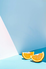 A minimalist composition of two orange slices against a soft blue and white background. Simple soft style.