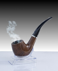 Smoking wooden pipe on stand. .