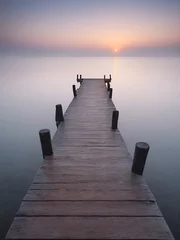 Foto op Plexiglas A wooden pier at misty dawn in a still sea © Эля Эля