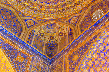 Interior of Madrasa Tilya Kori in Registan. Painted wall and part of dome. Arabic text of Qran (sacred book of muslims) used as part of ornament. April 24, 2023. Samarkand, Uzbekistan