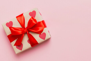 Top view photo of valentine day decorations gift box with red ribbon bow on colored background. Holiday gift boxes with top view