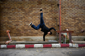 Shot of male hip hop dancer in stylish clothes dancing on city street sidewalk