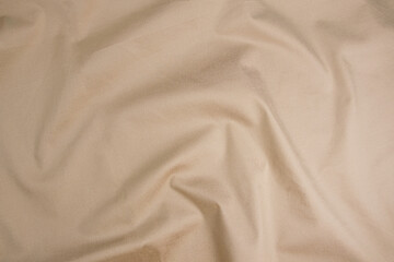 Texture of cotton fabric in gold-beige color, top view. Background, texture of draped fabric...