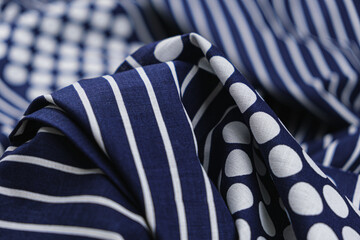 Close-up of texture of blue cotton fabric with a pattern of large polka dots and stripes of white colors. Background, texture of draped fabric with print.