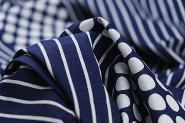 Close-up of texture of blue cotton fabric with a pattern of large polka dots and stripes of white...